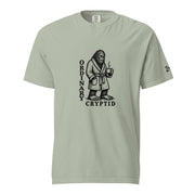 Black ink illustration of Bigfoot wearing a tied bathrobe and holding a steaming mug above the words “Ordinary Cryptid,” shown on a unisex t-shirt.