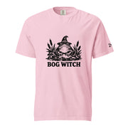 Black ink folk art illustration of a wide-eyed frog beneath an oversized pointed witch hat surrounded by cattails and marsh plants, with the words “BOG WITCH,” on a T-shirt.