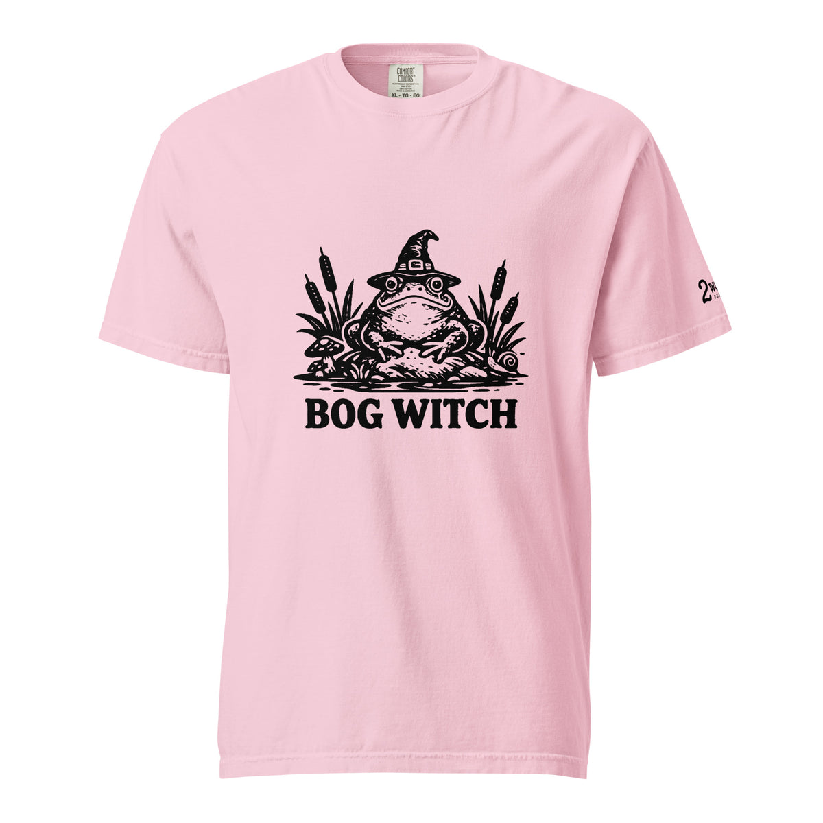 Black ink folk art illustration of a wide-eyed frog beneath an oversized pointed witch hat surrounded by cattails and marsh plants, with the words “BOG WITCH,” on a T-shirt.