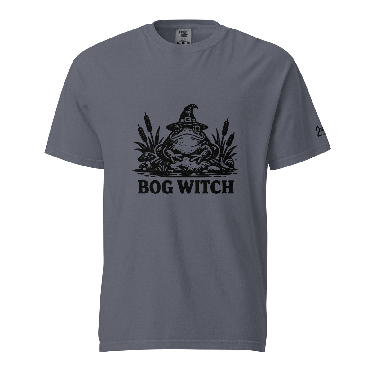 Black ink folk art illustration of a wide-eyed frog beneath an oversized pointed witch hat surrounded by cattails and marsh plants, with the words “BOG WITCH,” on a T-shirt.