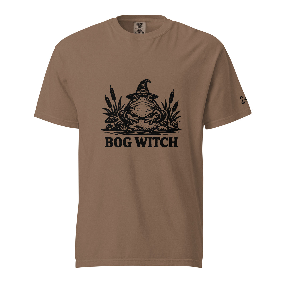 Black ink folk art illustration of a wide-eyed frog beneath an oversized pointed witch hat surrounded by cattails and marsh plants, with the words “BOG WITCH,” on a T-shirt.