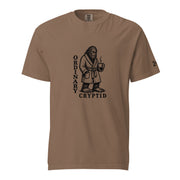 Black ink illustration of Bigfoot wearing a tied bathrobe and holding a steaming mug above the words “Ordinary Cryptid,” shown on a unisex t-shirt.