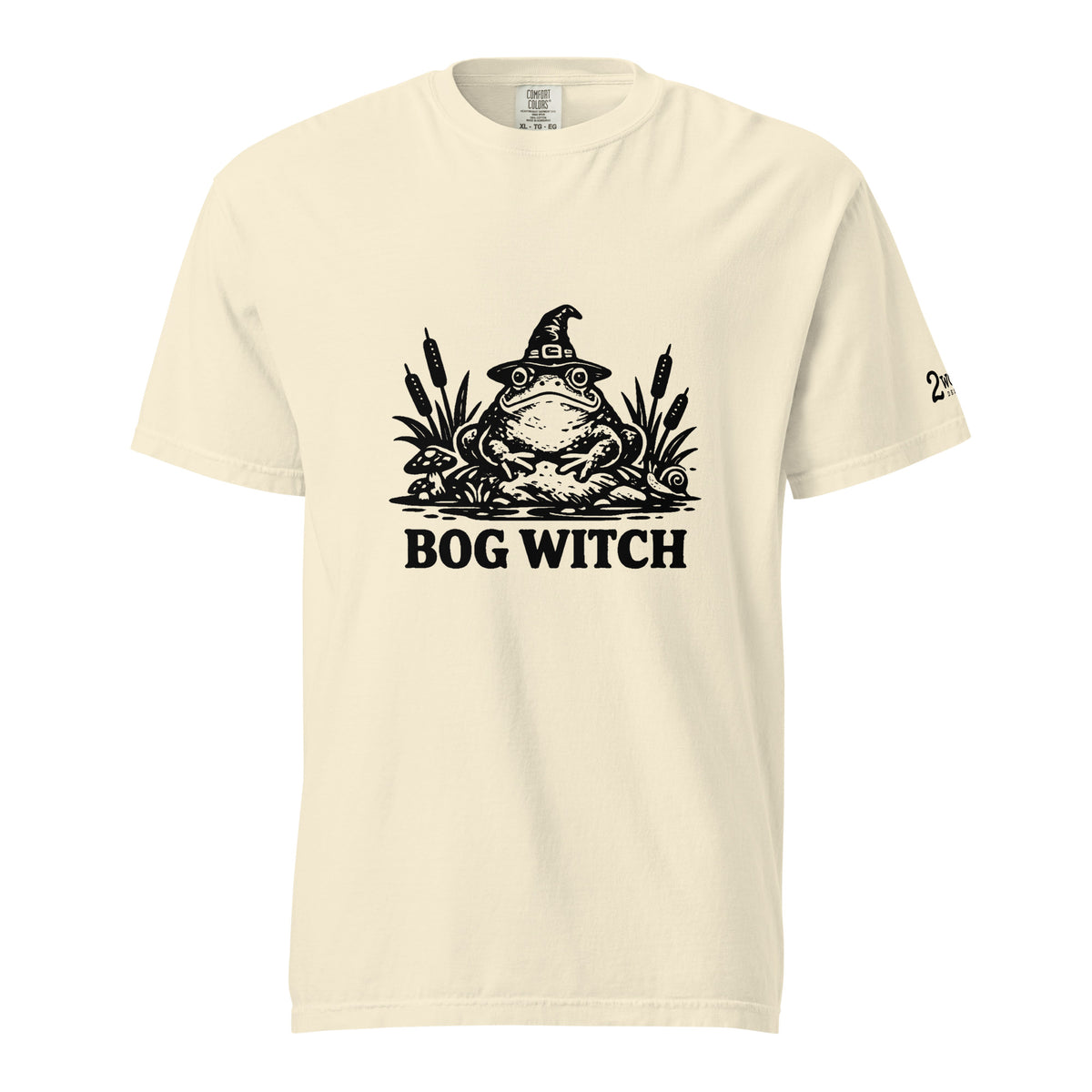 Black ink folk art illustration of a wide-eyed frog beneath an oversized pointed witch hat surrounded by cattails and marsh plants, with the words “BOG WITCH,” on a T-shirt.