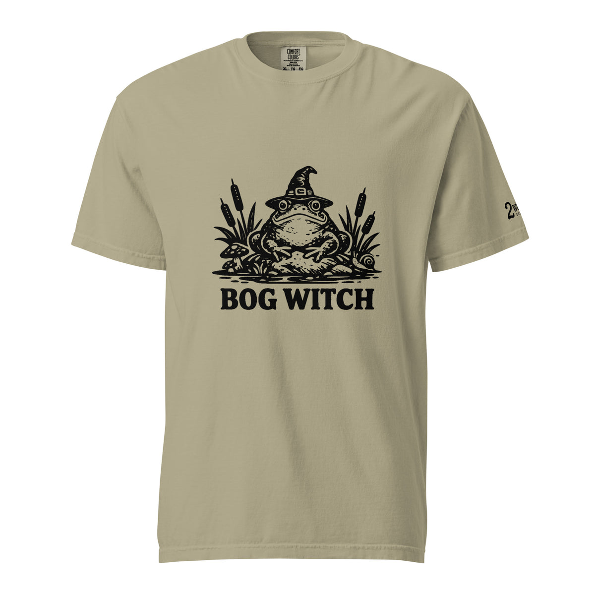 Black ink folk art illustration of a wide-eyed frog beneath an oversized pointed witch hat surrounded by cattails and marsh plants, with the words “BOG WITCH,” on a T-shirt.
