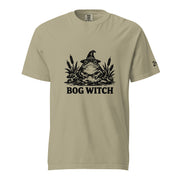 Black ink folk art illustration of a wide-eyed frog beneath an oversized pointed witch hat surrounded by cattails and marsh plants, with the words “BOG WITCH,” on a T-shirt.