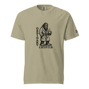 Black ink illustration of Bigfoot wearing a tied bathrobe and holding a steaming mug above the words “Ordinary Cryptid,” shown on a unisex t-shirt.