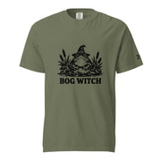 Black ink folk art illustration of a wide-eyed frog beneath an oversized pointed witch hat surrounded by cattails and marsh plants, with the words “BOG WITCH,” on a T-shirt.