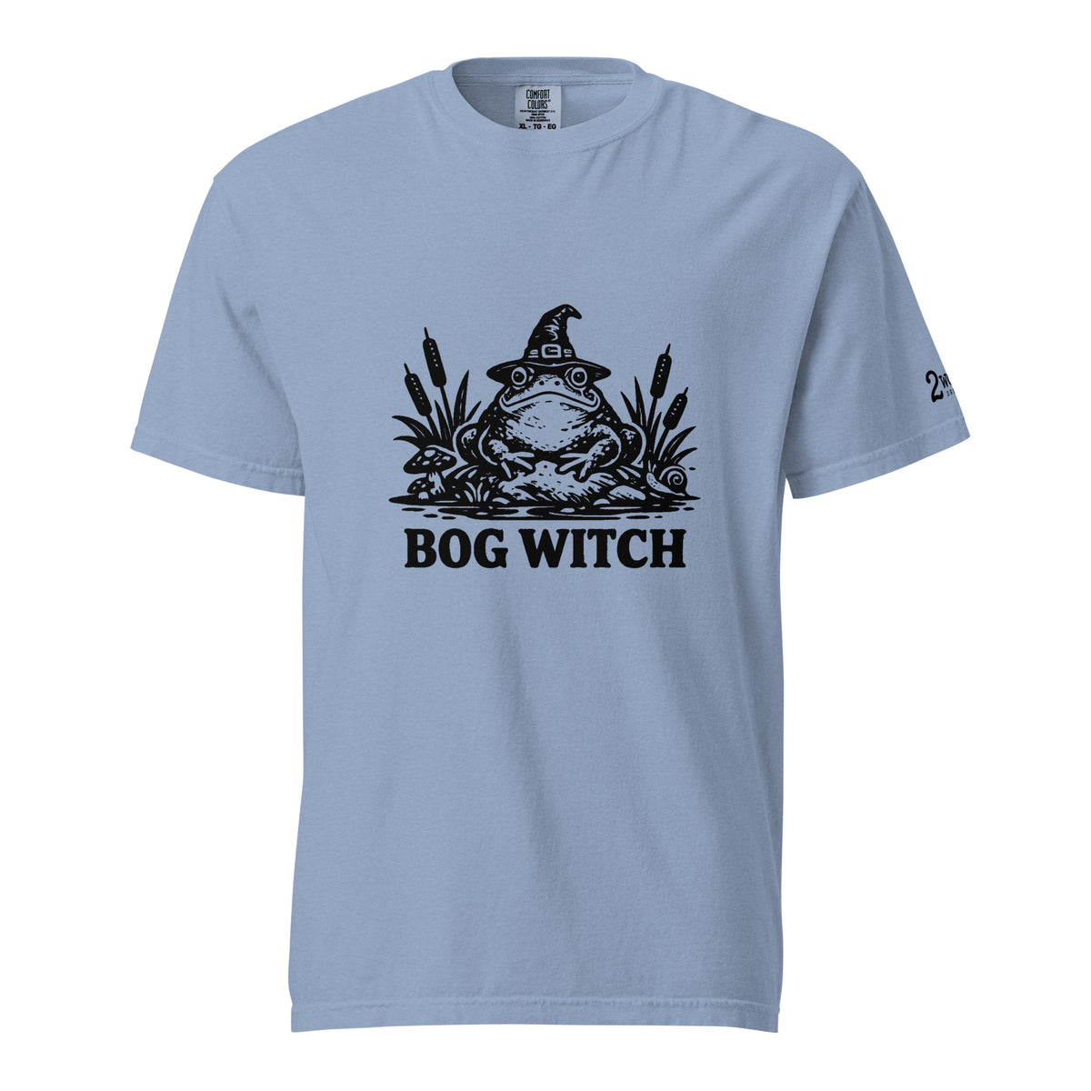 Black ink folk art illustration of a wide-eyed frog beneath an oversized pointed witch hat surrounded by cattails and marsh plants, with the words “BOG WITCH,” on a T-shirt.