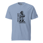 Black ink illustration of Bigfoot wearing a tied bathrobe and holding a steaming mug above the words “Ordinary Cryptid,” shown on a unisex t-shirt.