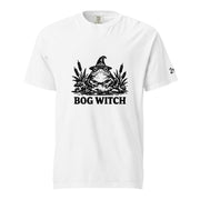 Black ink folk art illustration of a wide-eyed frog beneath an oversized pointed witch hat surrounded by cattails and marsh plants, with the words “BOG WITCH,” on a T-shirt.
