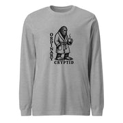 Black ink illustration of Bigfoot wearing a tied bathrobe and holding a steaming mug above the words “Ordinary Cryptid,” shown on a long sleeve tee.