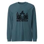Black ink folk art illustration of a wide-eyed frog beneath an oversized pointed witch hat surrounded by cattails and marsh plants, with the words “BOG WITCH,” on a long sleeve tee.