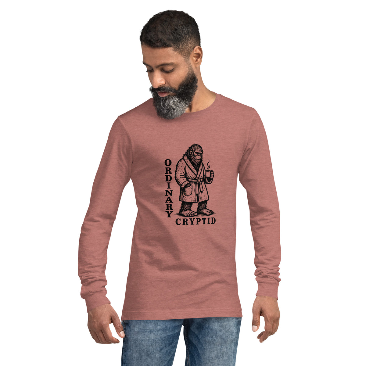 Black ink illustration of Bigfoot wearing a tied bathrobe and holding a steaming mug above the words “Ordinary Cryptid,” shown on a long sleeve tee.