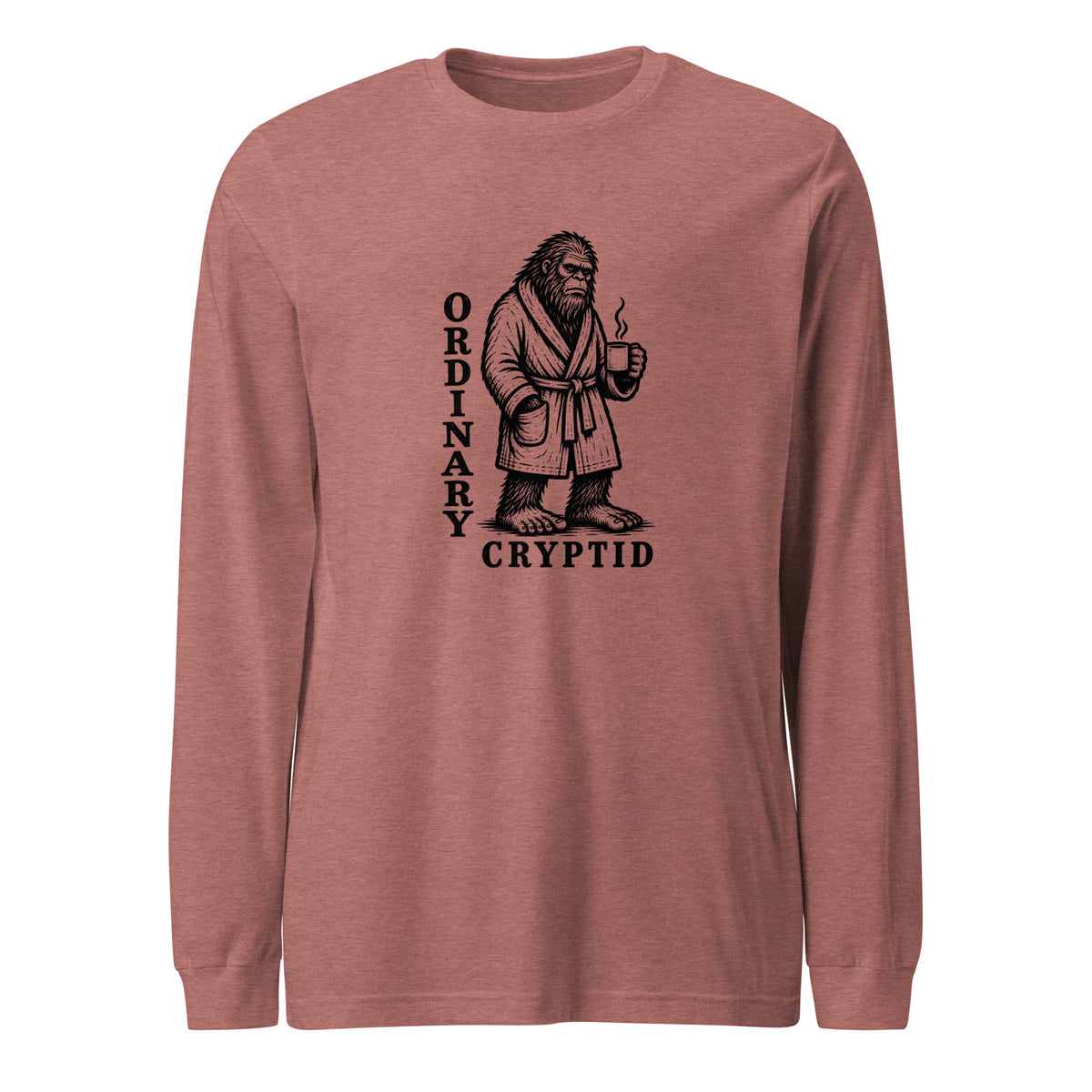 Black ink illustration of Bigfoot wearing a tied bathrobe and holding a steaming mug above the words “Ordinary Cryptid,” shown on a long sleeve tee.