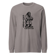 Black ink illustration of Bigfoot wearing a tied bathrobe and holding a steaming mug above the words “Ordinary Cryptid,” shown on a long sleeve tee.