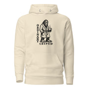 Black ink illustration of Bigfoot wearing a tied bathrobe and holding a steaming mug above the words “Ordinary Cryptid,” shown on a hoodie.