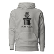 Black vintage-style illustration of a blooming flower growing from a magician's top hat with the words "Dirt Magic" beneath it, rendered in bold botanical line art inspired by classic storybook illustrations on a hoodie.