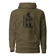 Black ink illustration of Bigfoot wearing a tied bathrobe and holding a steaming mug above the words “Ordinary Cryptid,” shown on a hoodie.