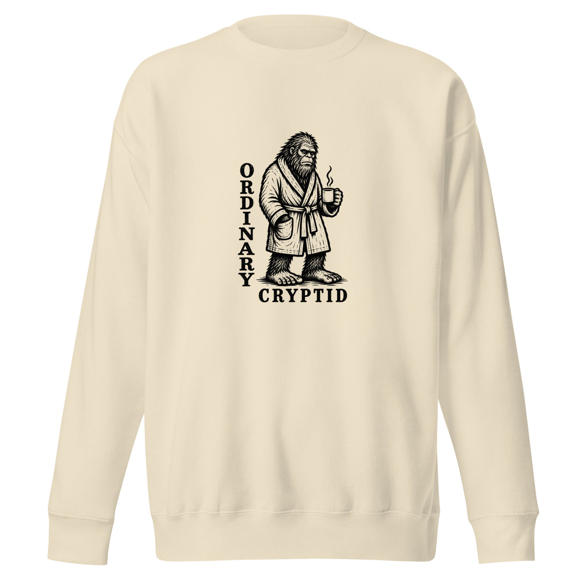 Black ink illustration of Bigfoot wearing a tied bathrobe and holding a steaming mug above the words “Ordinary Cryptid,” shown on a sweatshirt.