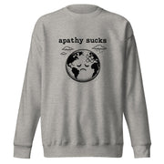 Vintage black-and-white linocut illustration of a sad Earth with a bandage on its forehead beneath rainy clouds and the words "Apathy Sucks" on a sweatshirt.