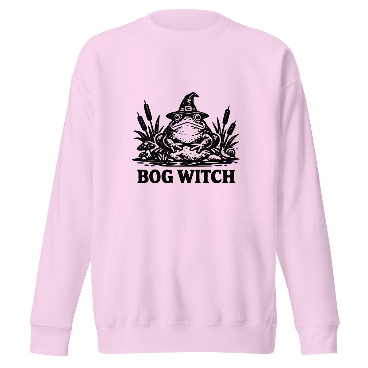 Black ink folk art illustration of a wide-eyed frog beneath an oversized pointed witch hat surrounded by cattails and marsh plants, with the words “BOG WITCH,” on a sweatshirt.